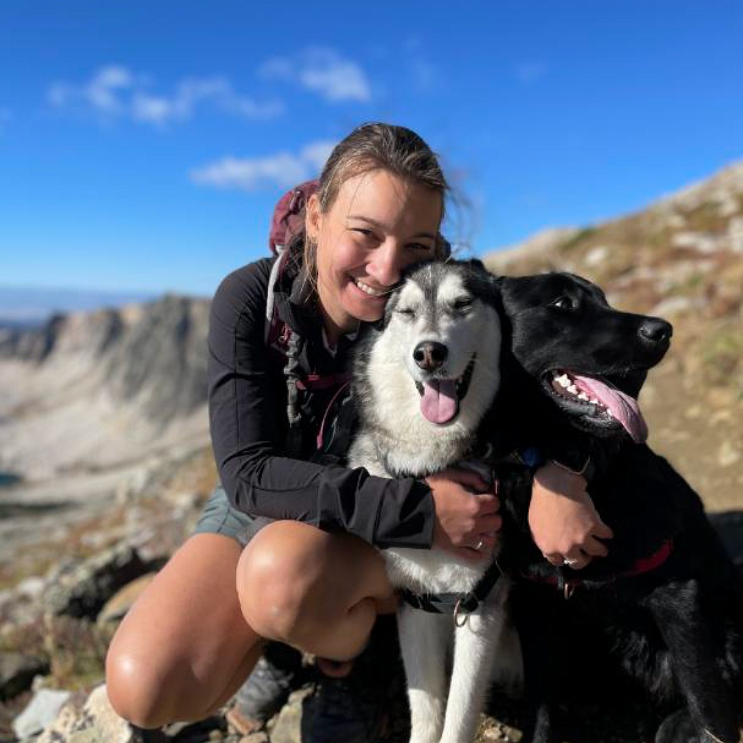 female outside posing with husky and black lab